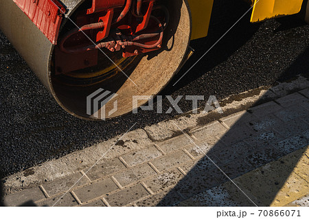 Asphalt road roller with heavy vibration roller compactor press new hot asphalt on the roadway on a road construction site. Heavy Vibration roller at asphalt pavement working. Repairing. Asphalt road roller with heavy vibration roller compactor press new hot asphalt on the roadway on a road construction site. Heavy Vibration roller at asphalt pavement working. Repairing. 70866071