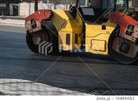 Asphalt road roller with heavy vibration roller compactor press new hot asphalt on the roadway on a road construction site. Heavy Vibration roller at asphalt pavement working. Repairing. Asphalt road roller with heavy vibration roller compactor press new hot asphalt on the roadway on a road construction site. Heavy Vibration roller at asphalt pavement working. Repairing. 70866083