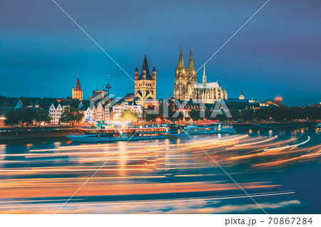 Cologne, Germany. Great St. Martin Church And Dom In Cologne At Evening With Reflection In River Rhine. Evening Blue Hour. Light Trails On Water From Pleasure Boats In Long Exposure Photography. 70867284