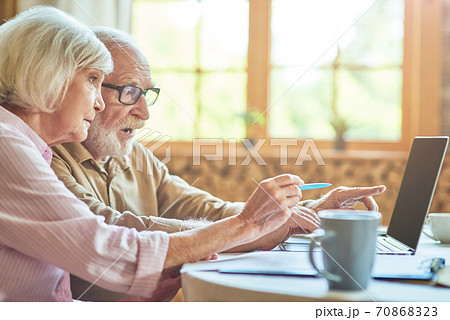 Gray-haired spouses working at the computer in the kitchen at home Gray-haired spouses working at the computer in the kitchen at home 70868323