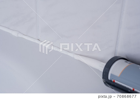 Plumber Applying silicone sealant to the tile joint 70868677