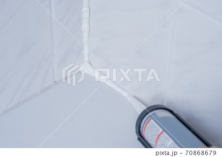Plumber Applying silicone sealant to the tile joint 70868679