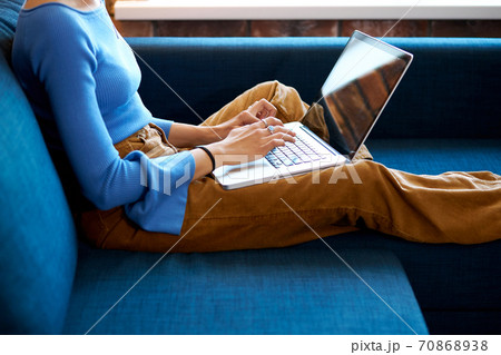 young woman sitting on sofa with laptop 70868938