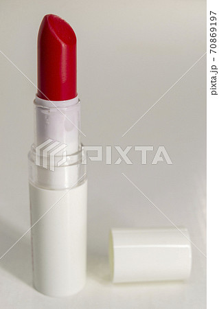 Red lipstick with a white background and cap lying next to it 70869197