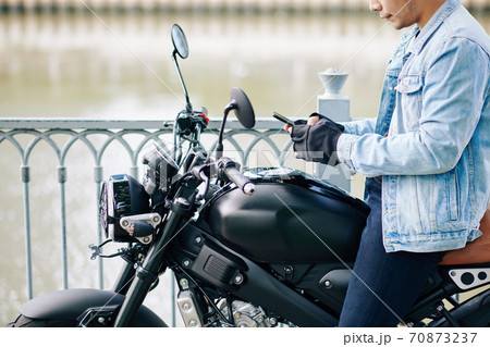 Motorcyclist checking phone 70873237