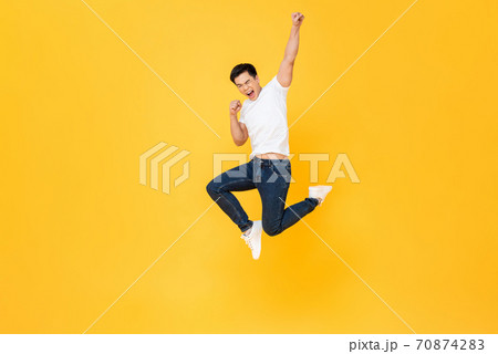 Young energetic Asian man jumping and raising his fist  70874283
