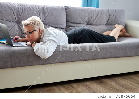 young caucasian teacher tired to sit on sofa with laptop, she is lying young caucasian teacher tired to sit on sofa with laptop, she is lying 70875654