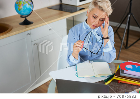 tired stressed young teacher woman sitting at her desk with books in front laptop 70875832
