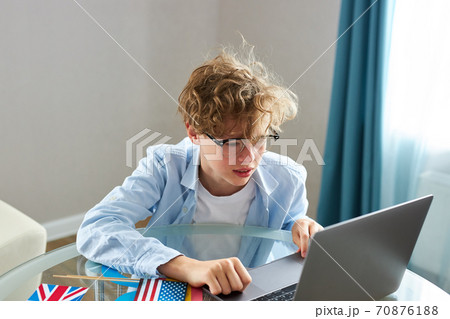 schoolboy is typing report on laptop, do homework 70876188