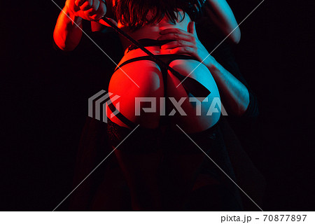 dominant man slaps a leather whip on the big ass of a submissive girl 70877897