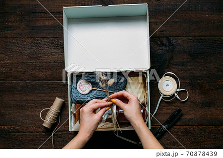 Care box, package ideas. Female hands fold a care box with sweets and warm clothes. Care Package Delivery, Fall Winter holidays Food Care gift box 70878439