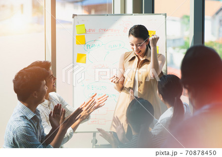 Asian woman entrepreneur raised her hands up smiling feeling success in the business meeting, concept of teamwork, brainstorming marketing plan, a confident businesswoman in work, startup business. 70878450
