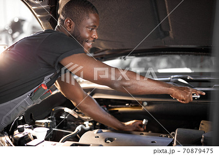 repairing in action. hardworking guy employee in uniform works in the automobile salon 70879475