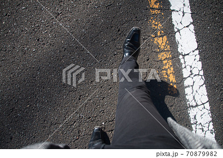 道路を歩く男性の足主観視点 冬 黒いズボンとコートの写真素材