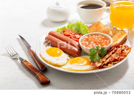 breakfast with plate of fried eggs, bacon, beans, sausages, toasts and tomatoes breakfast with plate of fried eggs, bacon, beans, sausages, toasts and tomatoes 70880053