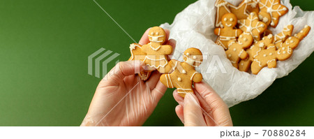Woman hands in protective gloves holding gingerbread man in facemask on natural shades of green background, pandemic new normal, 2021 New Year card, Christmas traditional sweetness, copy space Woman hands in protective gloves holding gingerbread man in facemask on natural shades of green background, pandemic new normal, 2021 New Year card, Christmas traditional sweetness, copy space 70880284