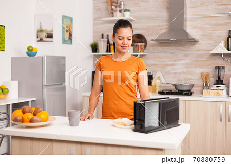 Woman using electric toaster Woman using electric toaster 70880759