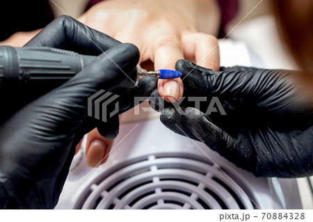 Manicurist applying electric nail file drill Manicurist applying electric nail file drill 70884328