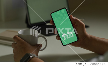 Male holding smartphone and coffee cup at workplace, include clipping path 70884656