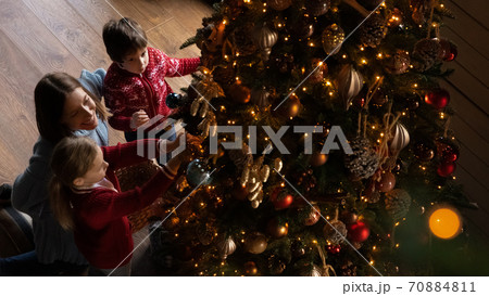 Banner view of mom and small kids decorate Christmas tree Banner view of mom and small kids decorate Christmas tree 70884811