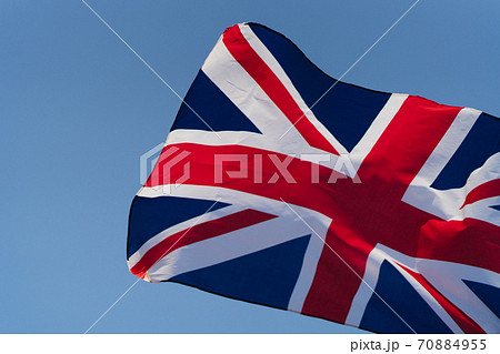 The flag of Great Britain develops in the wind at sunset against the sky. National symbol of England 70884955
