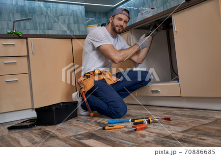 Young caucasian home master screwing part of kitchen furniture Young caucasian home master screwing part of kitchen furniture 70886685