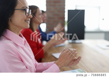 Business people sit at table smiling and clap their hands. Business people sit at table smiling and clap their hands. 70886885