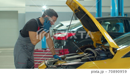 Mechanic calls customers for communication, in the car service center. Concept repair of machines fault diagnosis repair specialist, technical maintenance on-board computer. 70890959