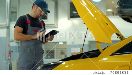 Car Service Manager Uses a Tablet Computer with an Augmented Reality Diagnostics Software. Car Service Manager Uses a Tablet Computer with an Augmented Reality Diagnostics Software. 70891351