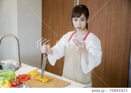 スマホを見て怒る女性 70893925