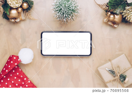Mockup smartphone with blank white screen, new year gift box with Xmas pine tree model, christmas ornaments, santa claus hat on wood background, top view, place for your artwork Mockup smartphone with blank white screen, new year gift box with Xmas pine tree model, christmas ornaments, santa claus hat on wood background, top view, place for your artwork 70895508