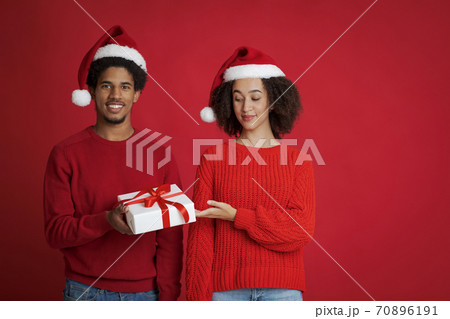 Winter holidays celebration. Young african american smiling man offering Christmas gift Winter holidays celebration. Young african american smiling man offering Christmas gift 70896191
