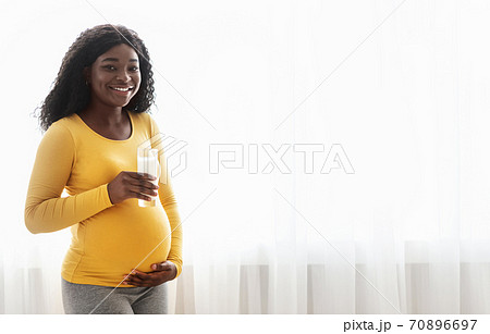 Cheerful african american pregnant woman holding glass of milk Cheerful african american pregnant woman holding glass of milk 70896697