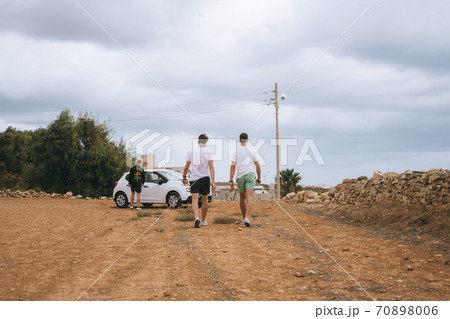 A group of people walking down a dirt road 70898006