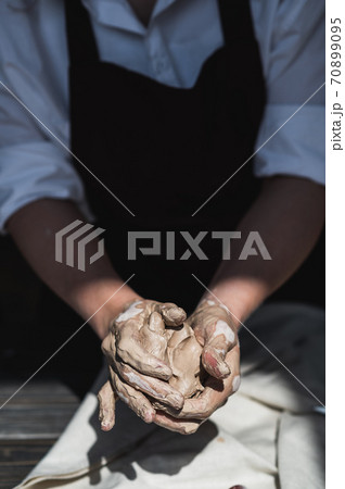 Close up of woman hands works with clay. Female potter kneads and moistens the clay before work. 70899095
