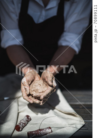 Wet hands covered with gray clay of potter holding raw piece of clay 70899111