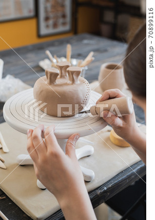 Child in the process of decorating the clay vase. Children pottery studio. 70899116
