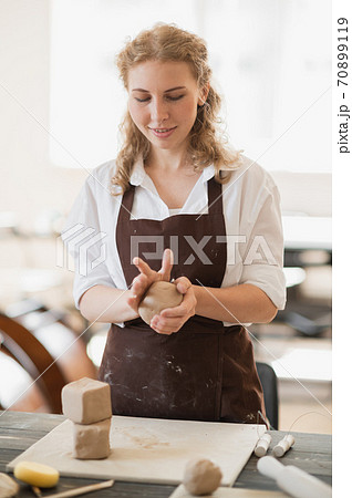 Female master kneads clay near wooden table on a pottery workshop 70899119