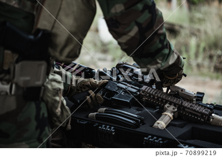 Military man with gun case takes out an assault rifle in destroyed city. Military and rescue operation concept. 70899219