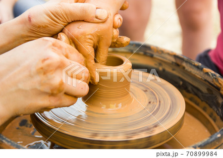 A close up view on ceramic production process on potter's wheel with children. Clay crafts with kids concept 70899984