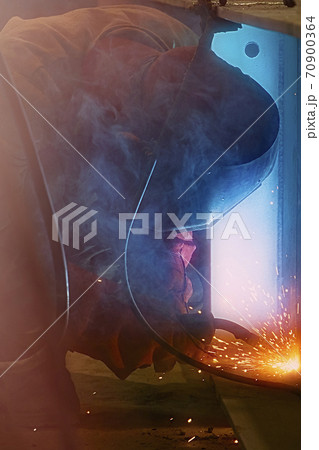Welder uses welding machine to make sparks during manufacture of metal construction 70900364