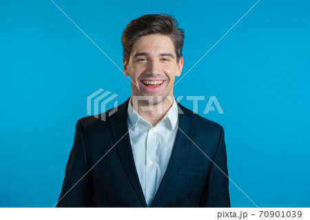Portrait of young successful confident businessman isolated on blue studio background. Man in Portrait of young successful confident businessman isolated on blue studio background. Man in 70901039