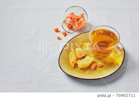Delicious black tea in glass cup and candied fruits on yellow saucer Delicious black tea in glass cup and candied fruits on yellow saucer 70902711