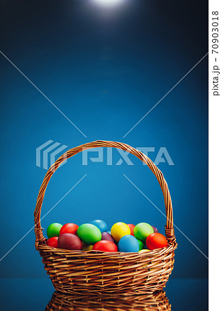 Easter color eggs in festive gift basket, blue background Easter color eggs in festive gift basket, blue background 70903018