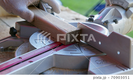 carpenter sets mitre saw angle 30 degrees and cuts wooden workpiece diagonally carpenter sets mitre saw angle 30 degrees and cuts wooden workpiece diagonally 70903051
