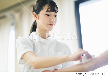 患者の腕を消毒する看護師 70904013
