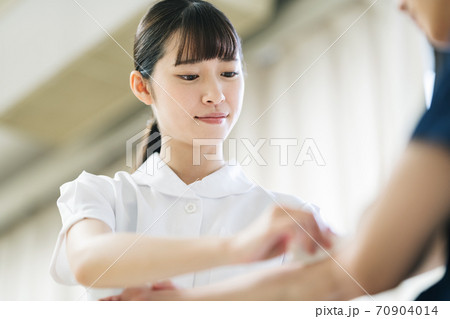 患者の腕を消毒する看護師 70904014