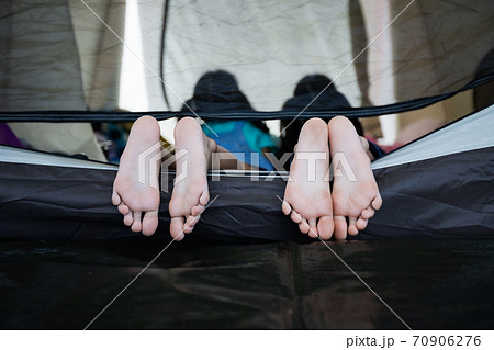 Close up on feets of two children while lying down and playing together in tent on campsite. Holiday and travel family camping concept. Close up on feets of two children while lying down and playing together in tent on campsite. Holiday and travel family camping concept. 70906276