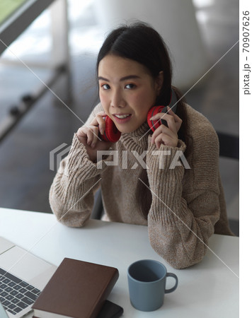 Female student relaxing with headphone in co working space Female student relaxing with headphone in co working space 70907626