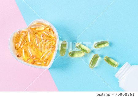 Fish oil capsules in white cup with bottle. 70908561